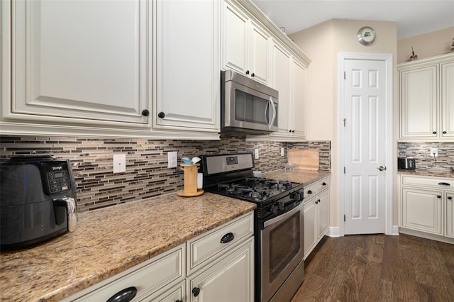 kitchen featuring white cabinets, light stone counters, dark wood-type flooring, and appliances with stainless steel finishes