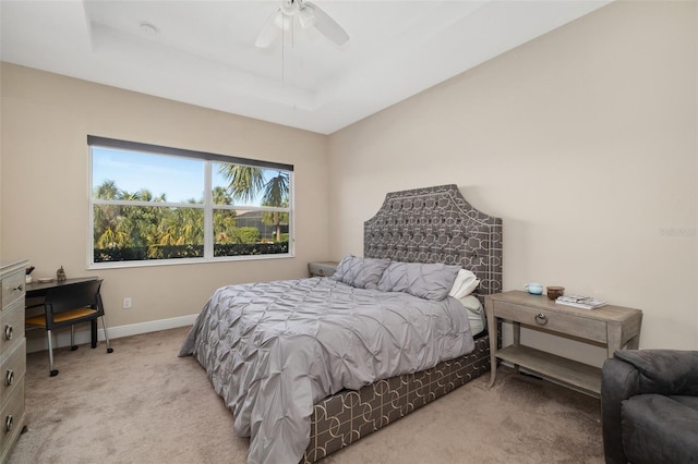 carpeted bedroom featuring a raised ceiling and ceiling fan