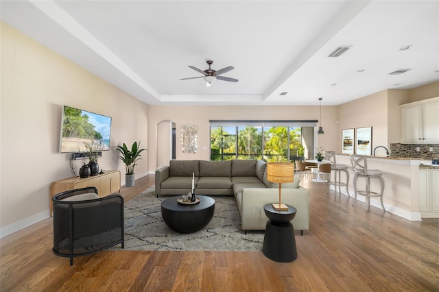 942 Preservation St, Bradenton, FL 34208 - living area featuring arched walkways, wood finished floors, a ceiling fan, a tray ceiling, and baseboards