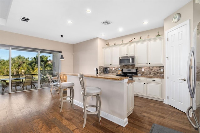 942 Preservation St, Bradenton, FL 34208 - kitchen featuring stainless steel appliances, backsplash, dark wood-type flooring, white cabinets, and a kitchen bar