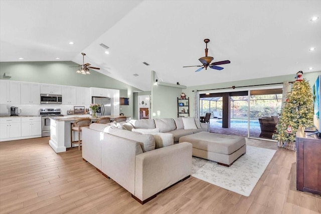 living room with ceiling fan, light wood-type flooring, and high vaulted ceiling