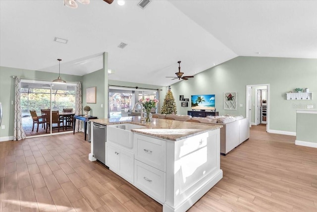 kitchen with ceiling fan, dishwasher, vaulted ceiling, a kitchen island with sink, and white cabinets