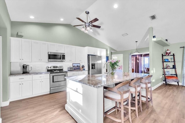 kitchen featuring stainless steel appliances, white cabinetry, and an island with sink