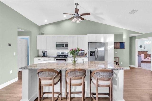 kitchen with light stone countertops, white cabinetry, a center island with sink, and stainless steel appliances