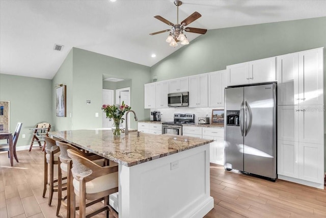 kitchen featuring backsplash, white cabinetry, an island with sink, and appliances with stainless steel finishes