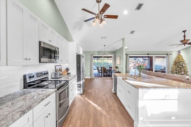 kitchen with light stone counters, light hardwood / wood-style flooring, vaulted ceiling, white cabinets, and appliances with stainless steel finishes