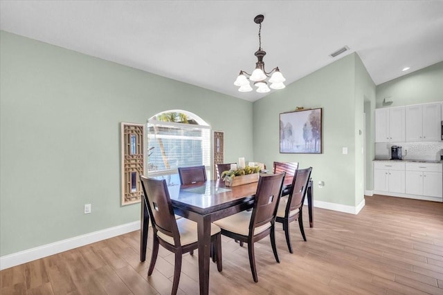 dining area featuring light hardwood / wood-style floors, vaulted ceiling, and a notable chandelier