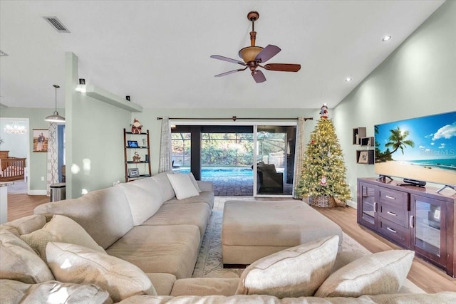 living room featuring vaulted ceiling, light hardwood / wood-style flooring, and ceiling fan