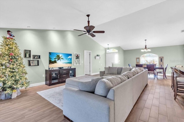 living room with ceiling fan with notable chandelier, light wood-type flooring, and high vaulted ceiling