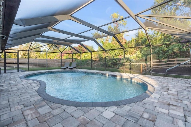 view of pool featuring glass enclosure and a patio