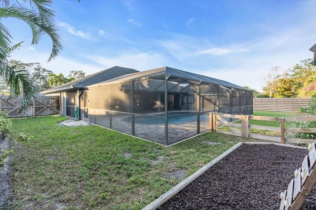 rear view of house with a lanai, a patio area, a yard, and a fenced in pool