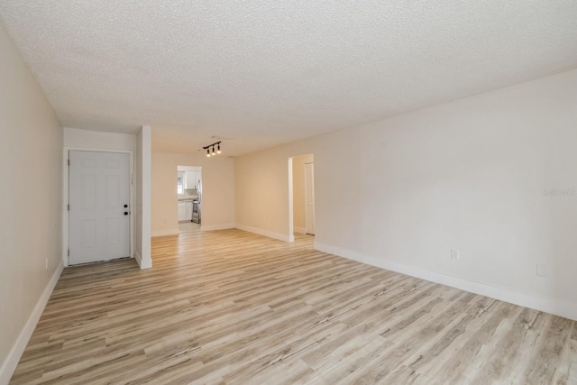 empty room with light hardwood / wood-style floors and a textured ceiling