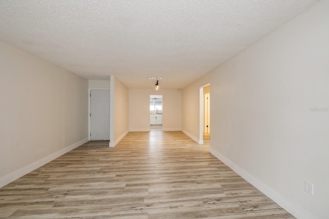 unfurnished room featuring light wood-type flooring and a textured ceiling