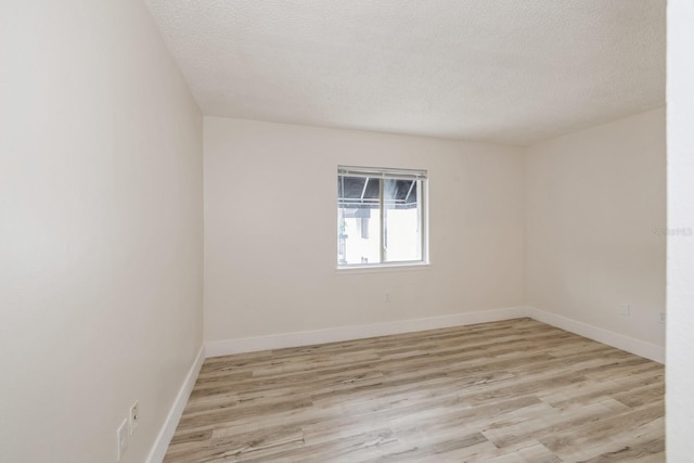 spare room with light hardwood / wood-style floors and a textured ceiling