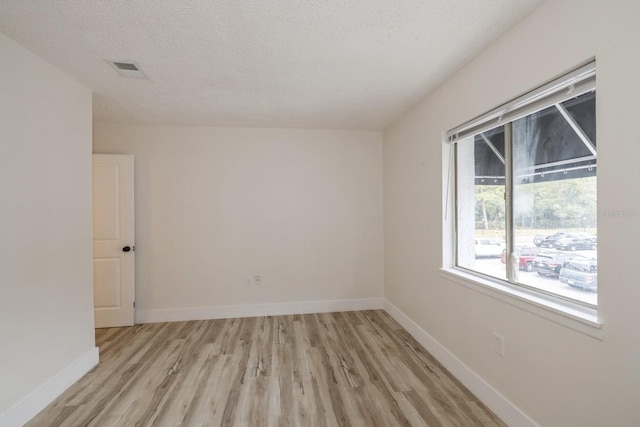 unfurnished room featuring a textured ceiling and light hardwood / wood-style floors