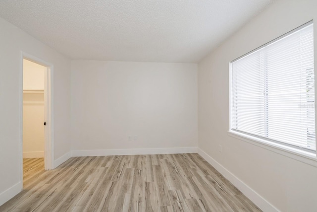 unfurnished room featuring a textured ceiling and light hardwood / wood-style flooring