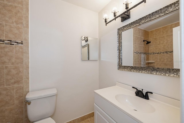 bathroom with vanity, tiled shower, and toilet