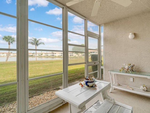 sunroom featuring ceiling fan and a water view