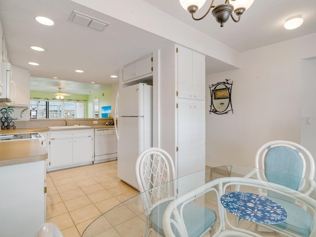 kitchen with sink, white cabinets, light tile patterned floors, white appliances, and ceiling fan with notable chandelier