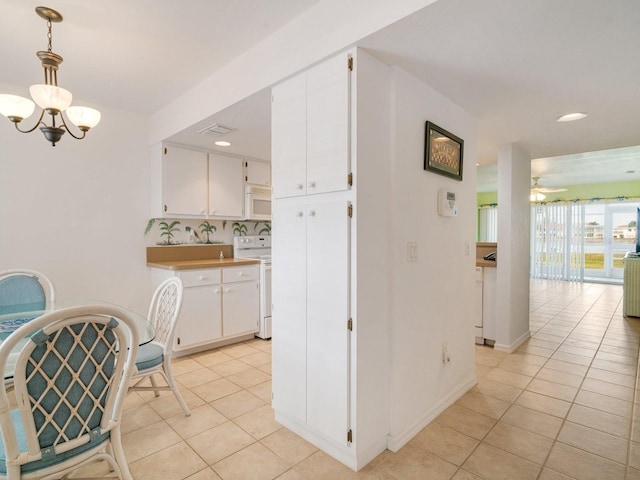 kitchen featuring hanging light fixtures, white cabinets, range, and light tile patterned flooring