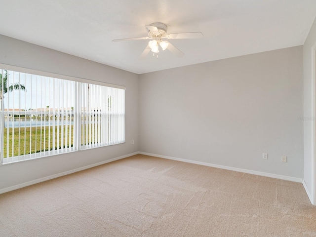 carpeted empty room with ceiling fan and a water view