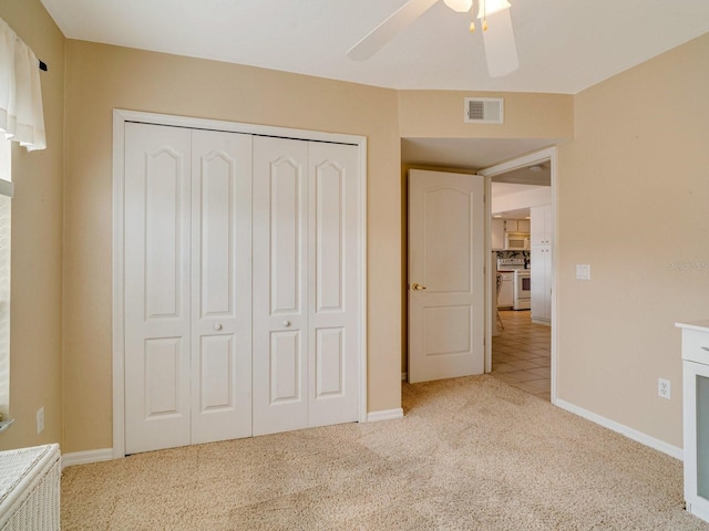 unfurnished bedroom with light colored carpet, a closet, and ceiling fan