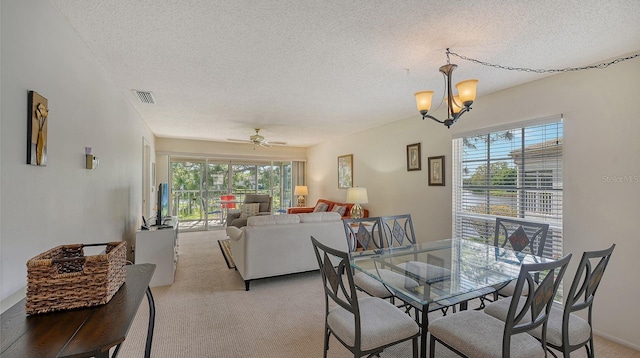 dining area featuring a textured ceiling, ceiling fan with notable chandelier, and light colored carpet