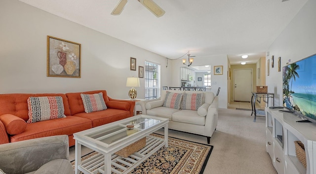 carpeted living room featuring ceiling fan with notable chandelier