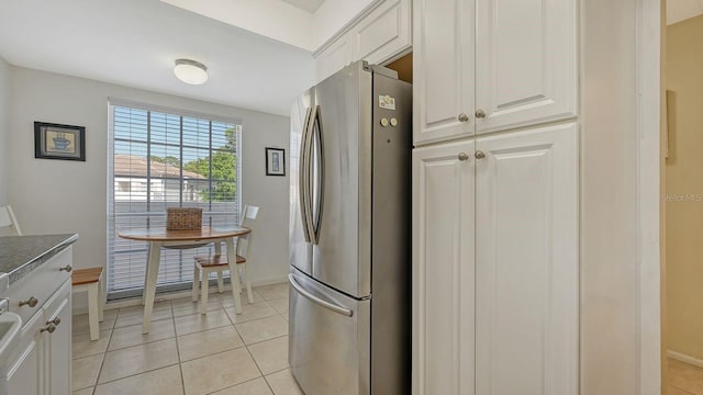 kitchen with white cabinetry, stainless steel fridge, and light tile patterned floors