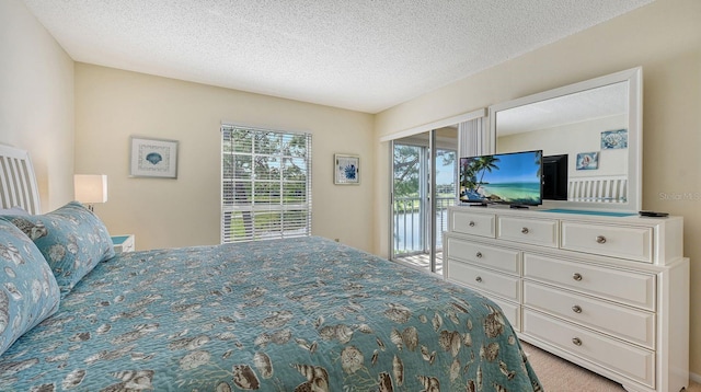 carpeted bedroom with a textured ceiling and access to outside