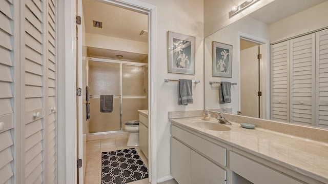 bathroom featuring tile patterned flooring, vanity, toilet, and walk in shower