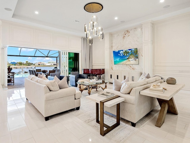 living room with a raised ceiling, crown molding, light tile patterned flooring, and an inviting chandelier