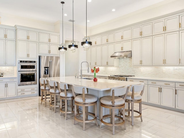 kitchen featuring a kitchen bar, a kitchen island with sink, and stainless steel appliances