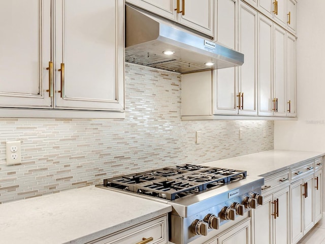 kitchen with light stone counters, backsplash, and stainless steel gas cooktop