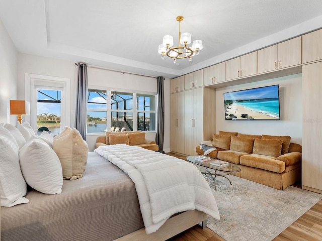 bedroom with a tray ceiling, light hardwood / wood-style flooring, and a notable chandelier