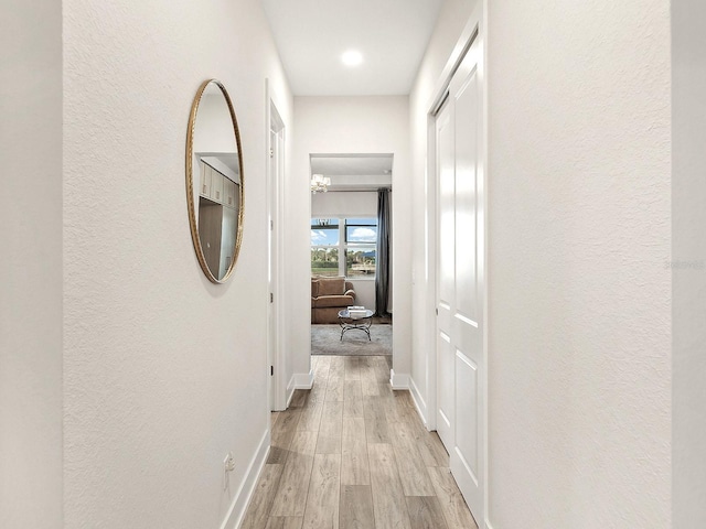 hall with a chandelier and light wood-type flooring