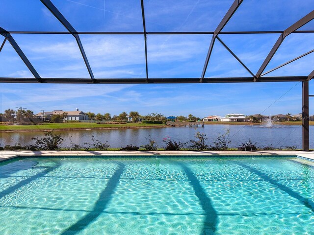 view of swimming pool with glass enclosure and a water view