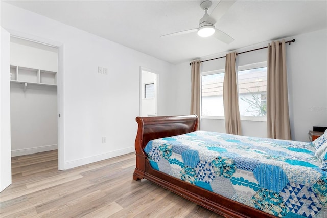 bedroom with light wood-type flooring, a walk in closet, a closet, and ceiling fan