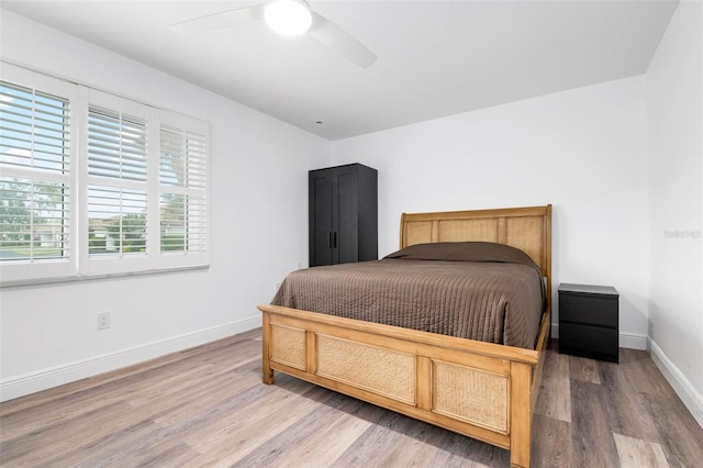 bedroom with multiple windows, ceiling fan, and hardwood / wood-style floors