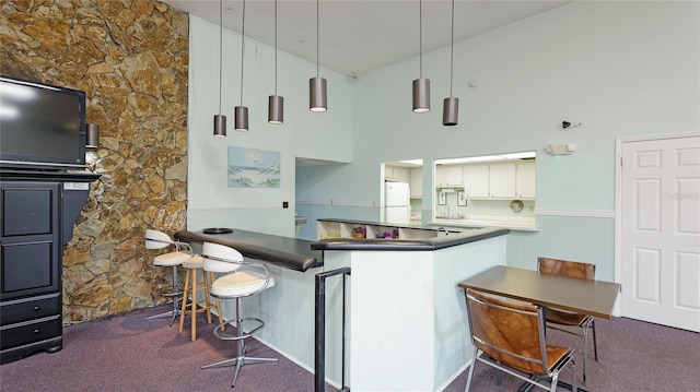 kitchen featuring pendant lighting, a high ceiling, dark carpet, kitchen peninsula, and white fridge