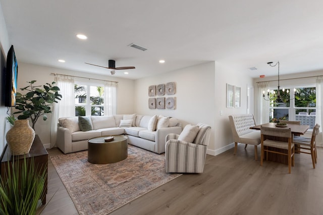 living room with ceiling fan with notable chandelier and hardwood / wood-style flooring