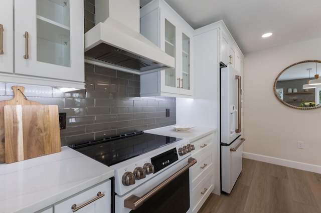 kitchen with tasteful backsplash, light hardwood / wood-style floors, white appliances, white cabinets, and custom range hood