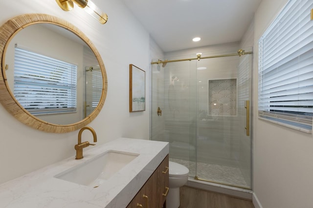 bathroom with hardwood / wood-style floors, vanity, an enclosed shower, and toilet