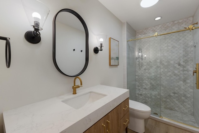 bathroom featuring a shower with door, vanity, hardwood / wood-style floors, and toilet