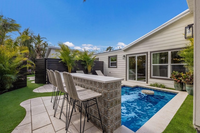 view of swimming pool featuring a lawn, a patio area, and exterior bar