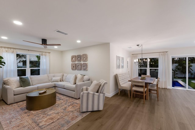 living room featuring wood-type flooring and ceiling fan with notable chandelier