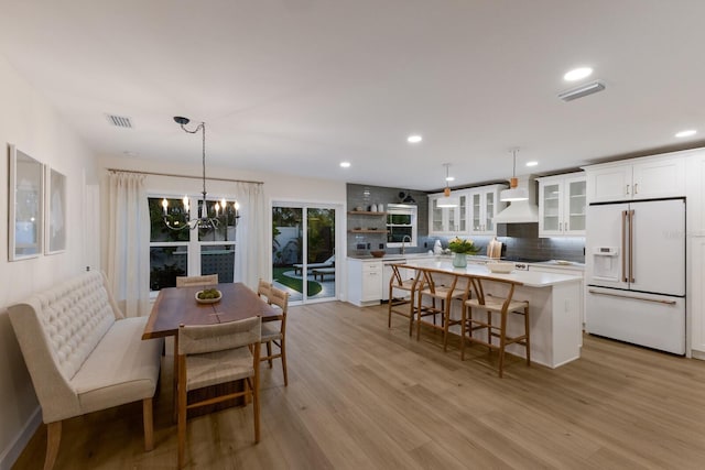 kitchen with white cabinets, decorative light fixtures, white appliances, and a center island