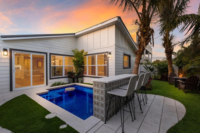 back house at dusk featuring a patio and an outdoor bar