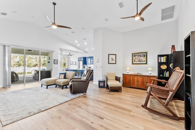 living room with ceiling fan, light hardwood / wood-style floors, and high vaulted ceiling