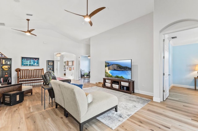 living room with ceiling fan, high vaulted ceiling, and light hardwood / wood-style flooring